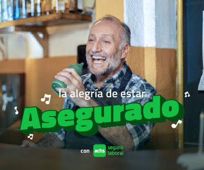 Hombre sonriente con delantal en su negocio ilustra campaña Achs Seguro Laboral sobre la alegría de estar asegurado como parte de una empresa, pyme o independiente.